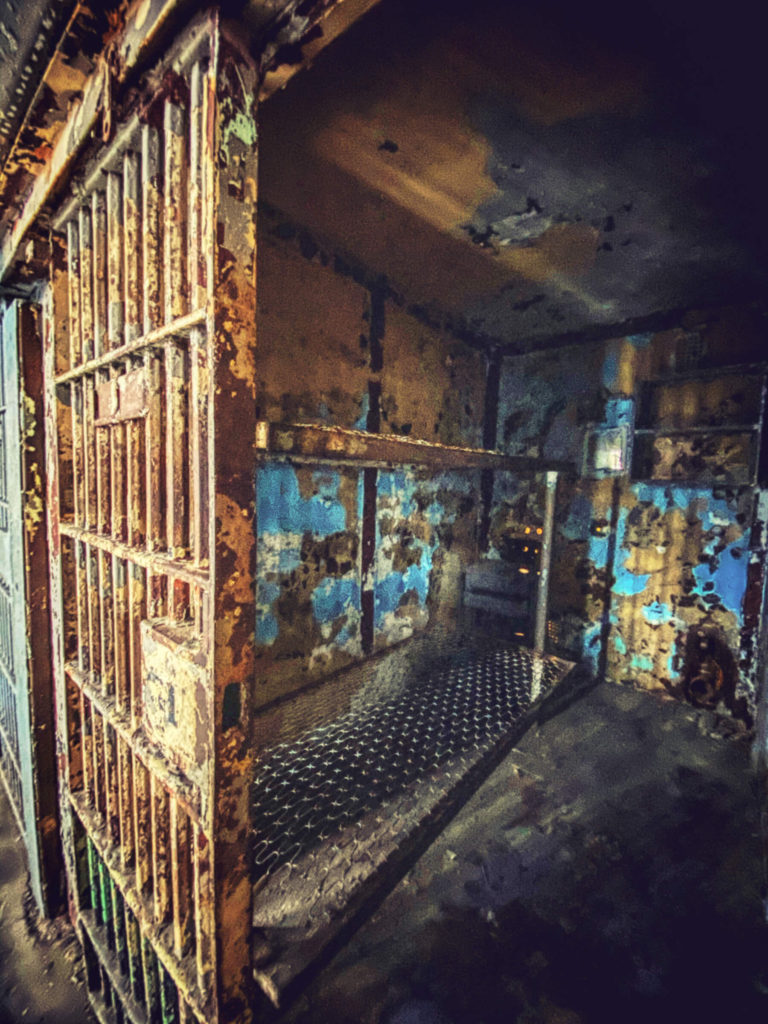 Looking into cell at the Mansfield Reformatory. Bunkbeds frames against a blue wall.